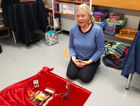 Gudrun Rathke sitz vor einer roten Decke mit Gegenständen